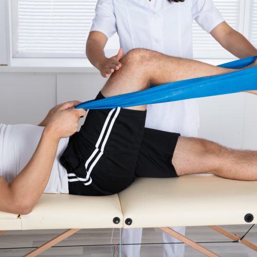 Physiotherapist Helping Patient While Stretching His Leg